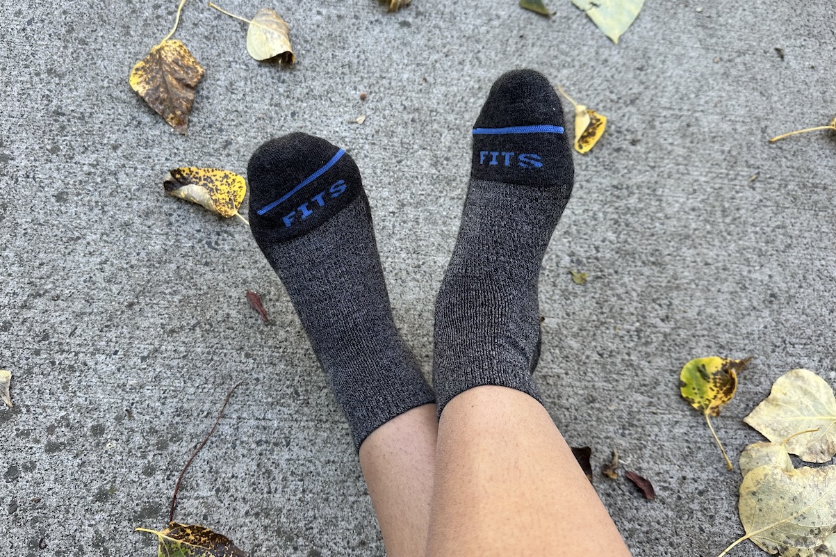 Feet in a pair of Fits Socks are stretched out in front of the camera