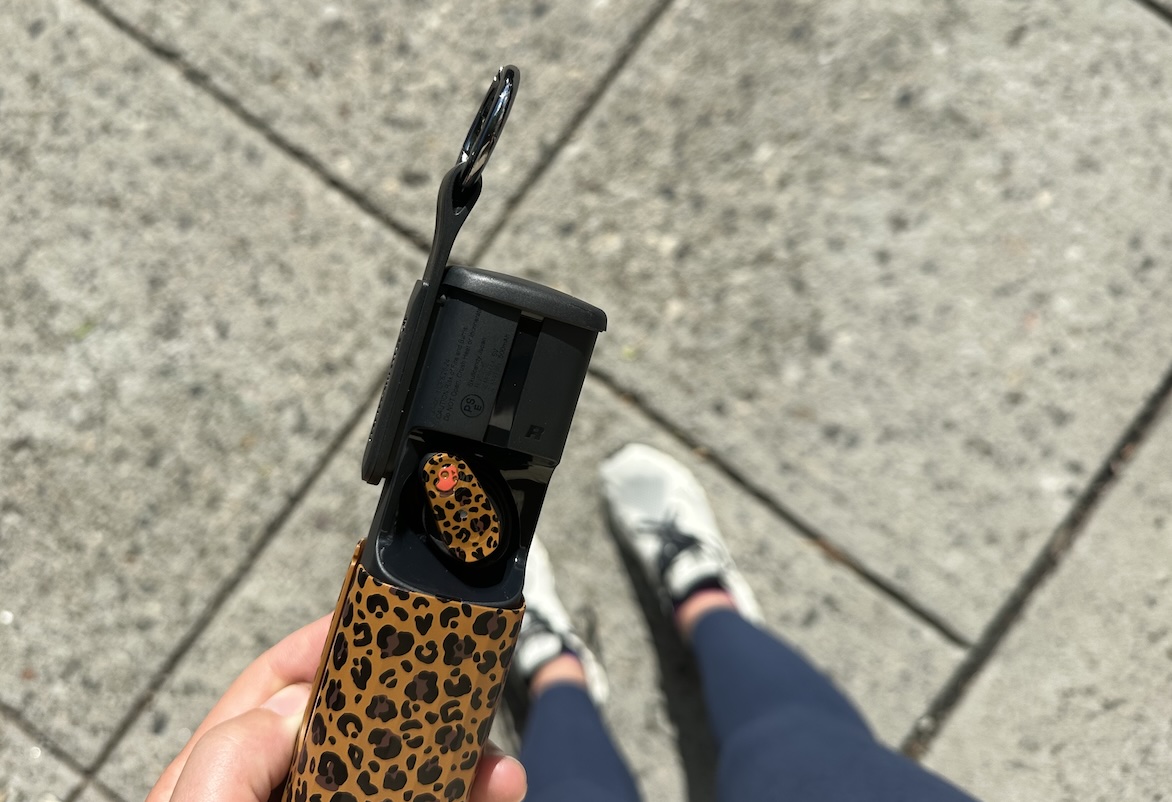 A woman holds out a pair of earbuds from skullcandy in a leopard print patter