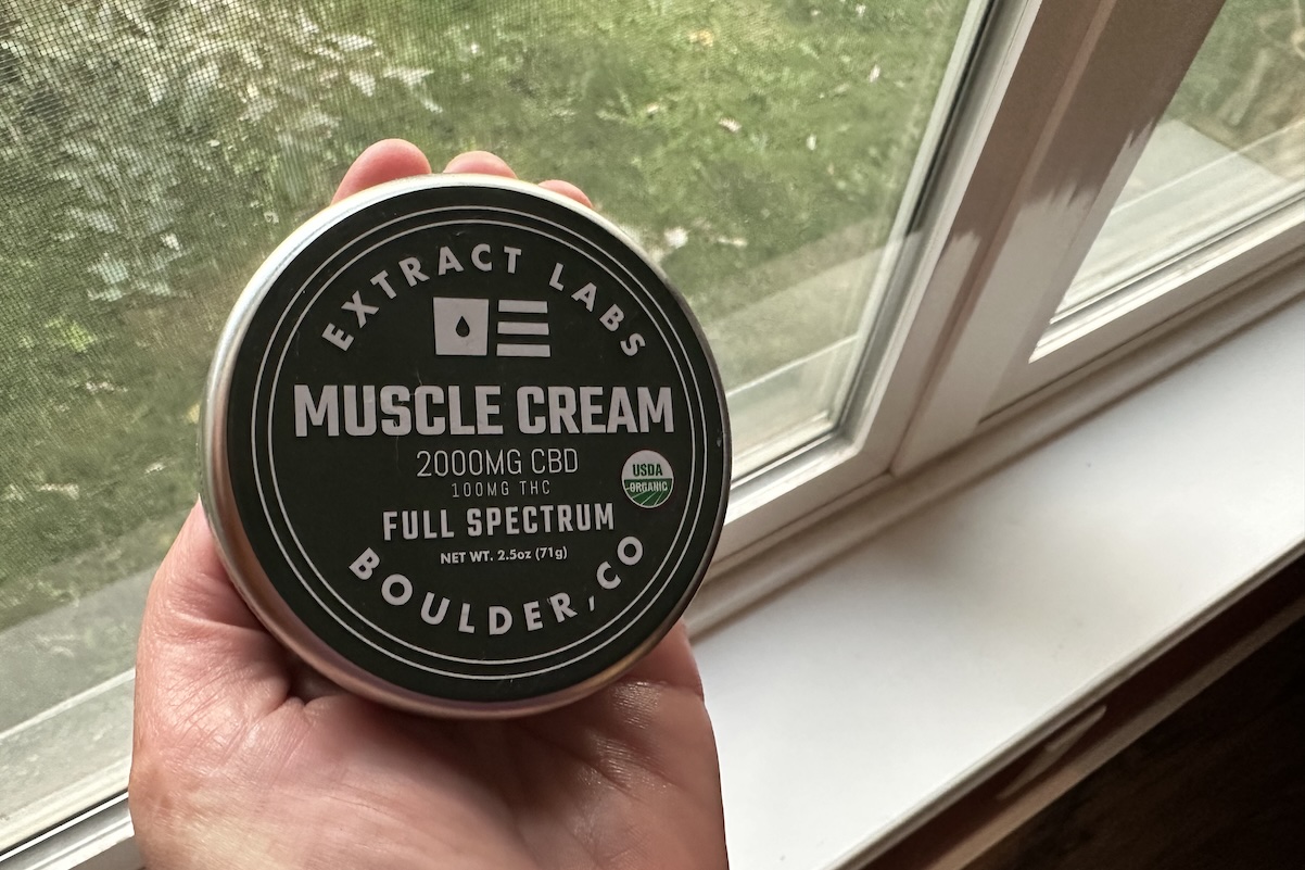A woman holds up extract labs CBD muscle cream as a recovery tool for runners