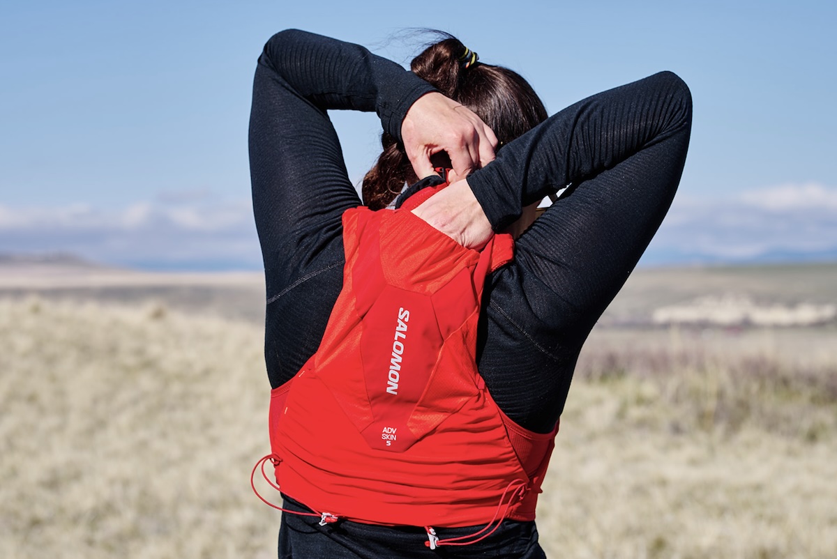 a woman is shown from behind wearing a red running pack 