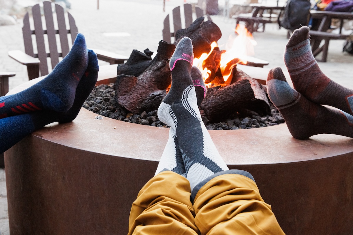 A group of skiers put their sock-laden feet up around a firepit