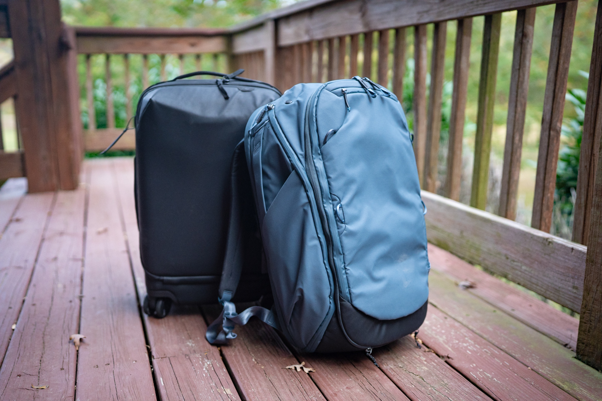 A Peak Design travel backpack is sitting on a porch, packed and ready for travel.