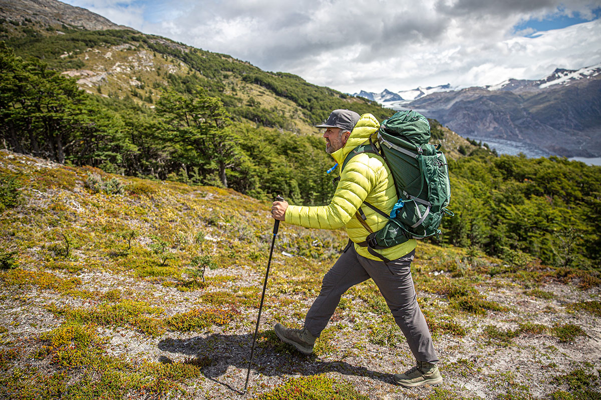 A man in a yellow down jacket and large backpack hiking in Patagonia