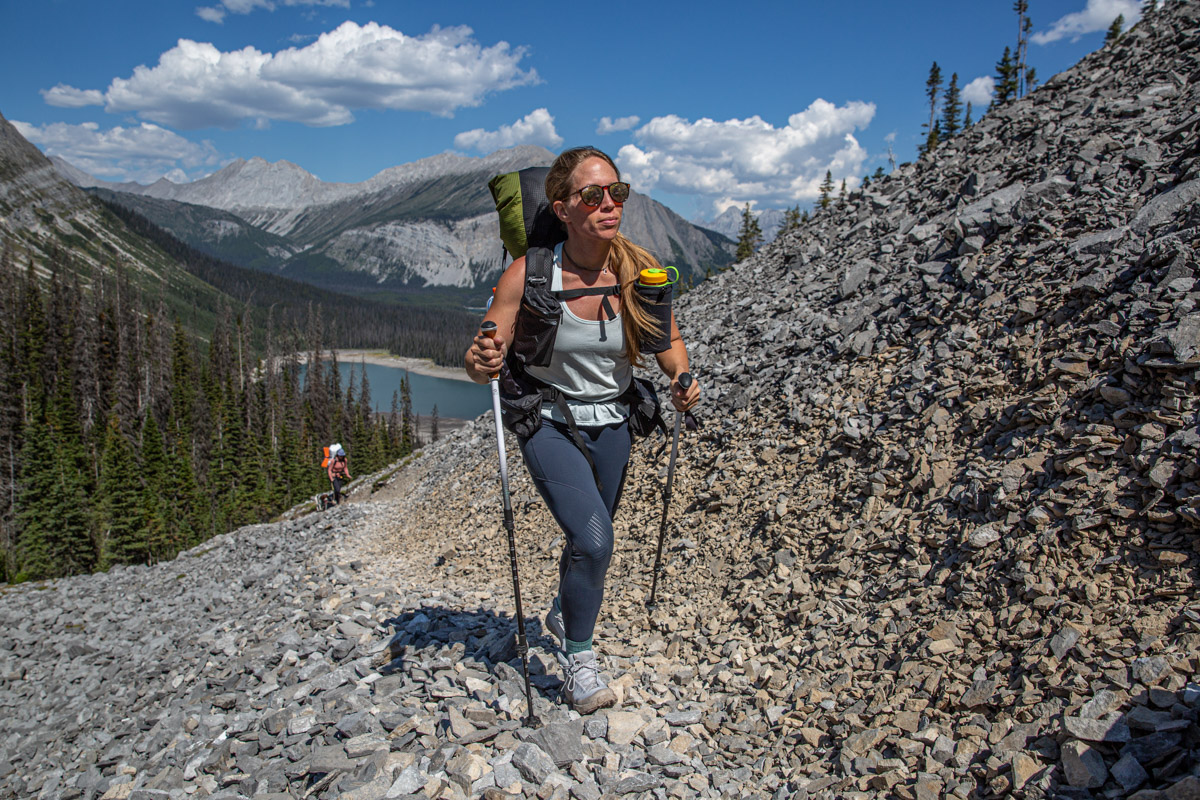 A woman hiking up a rocky trail wearing white hiking boots