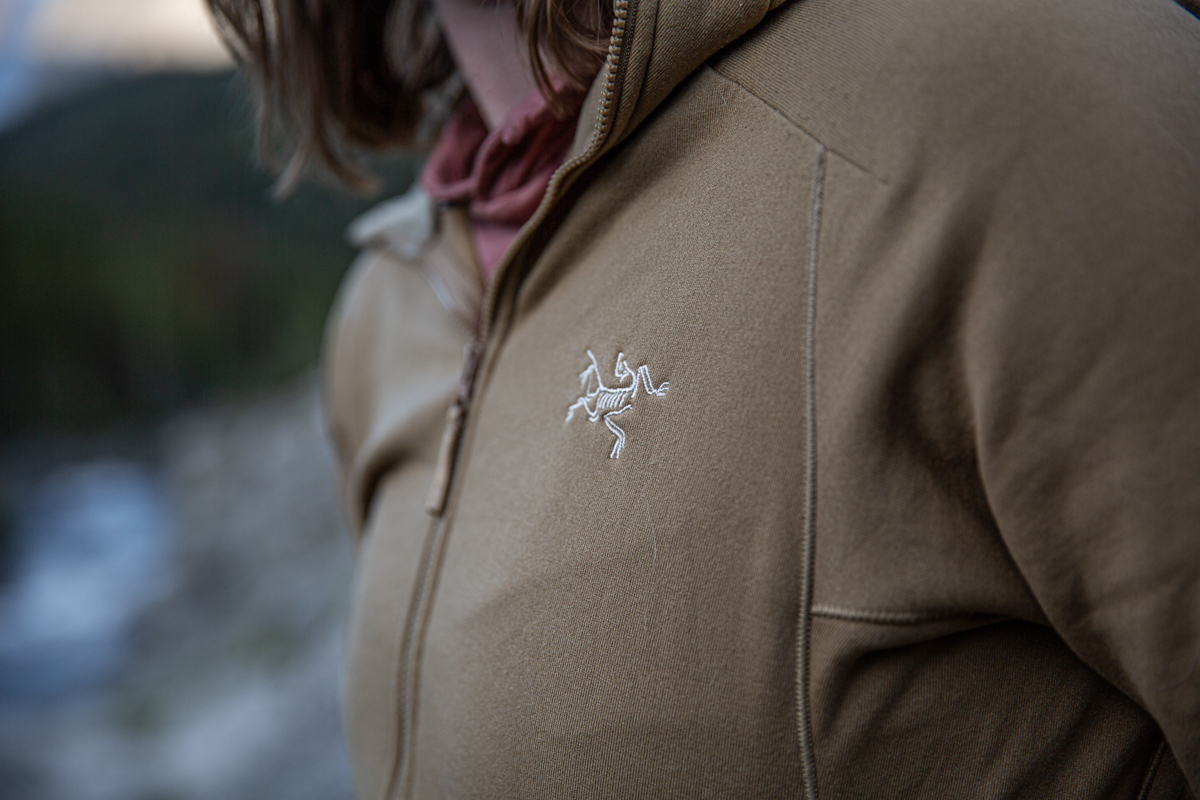 A close up of a white Arc'teryx logo on a brown fleece jacket