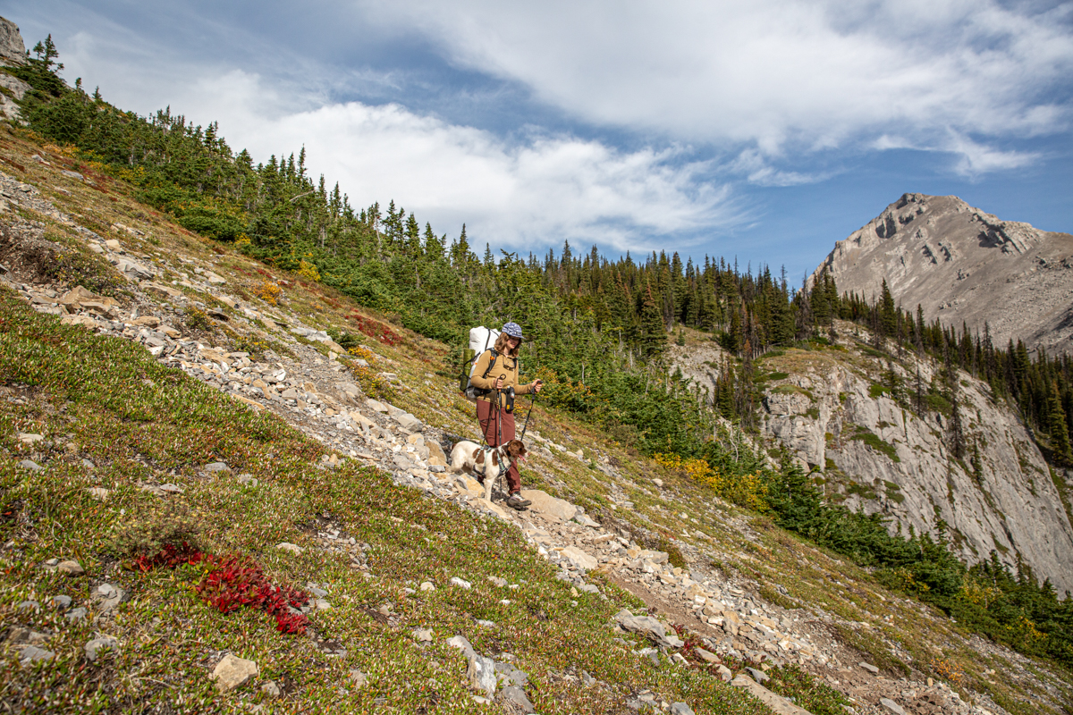 A woman hiking down a steep trail in a brown fleece jacket
