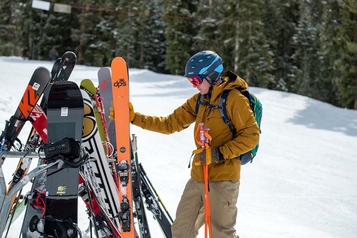 A skiier gathers his skiis from a rack at the resort.