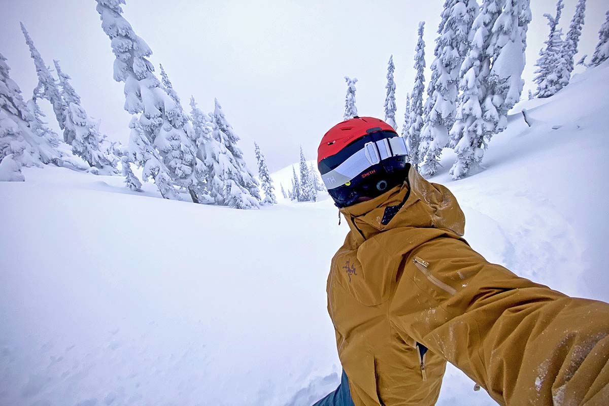 A skiier looks down a fluffy, powdery, snow-white ski descent among the trees.