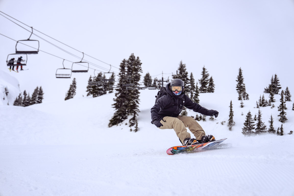 A woman snowboarding quickly wearing snowboard pants