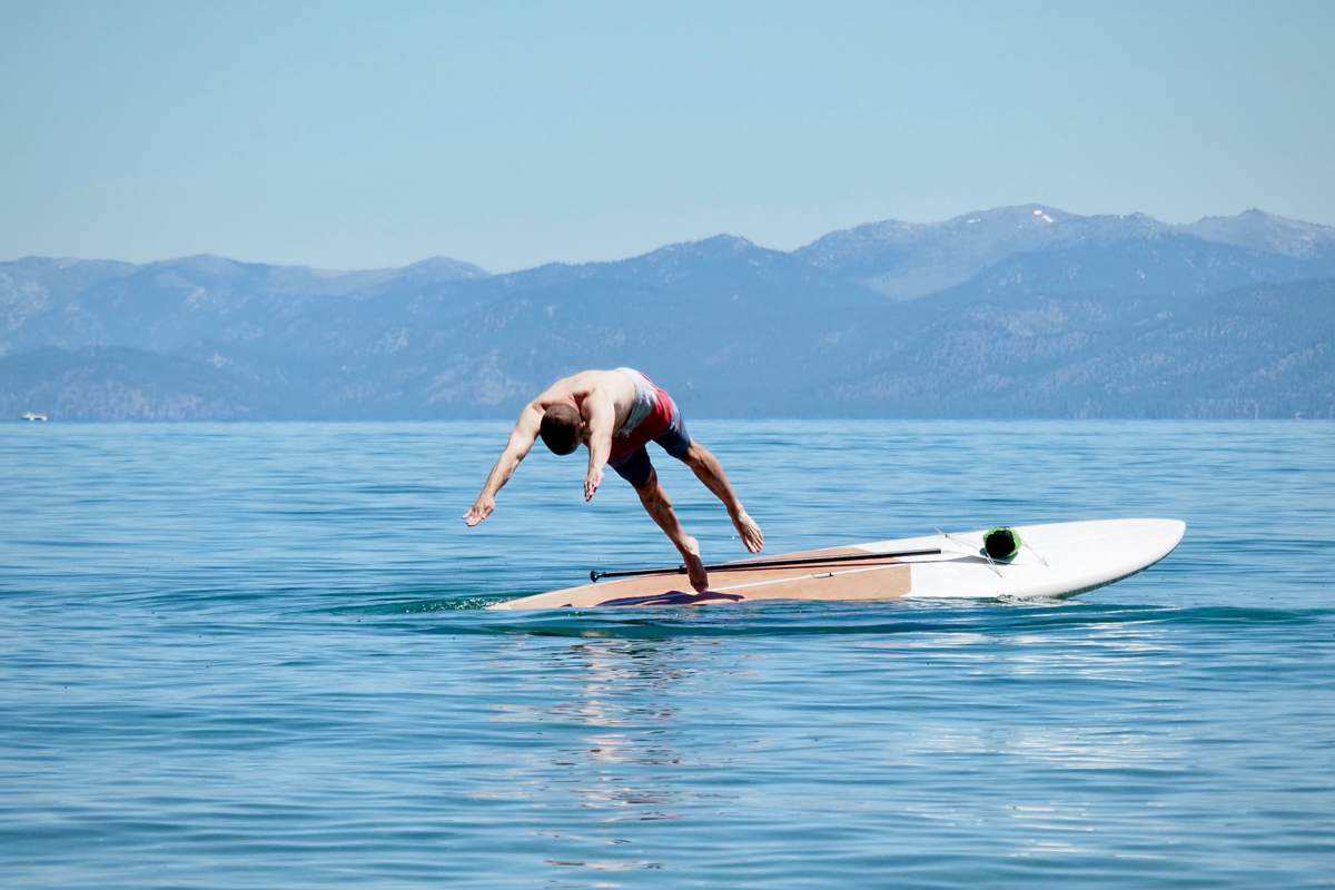 A man diving into Lake Tahoe from the Dax DownDog stand up paddle board