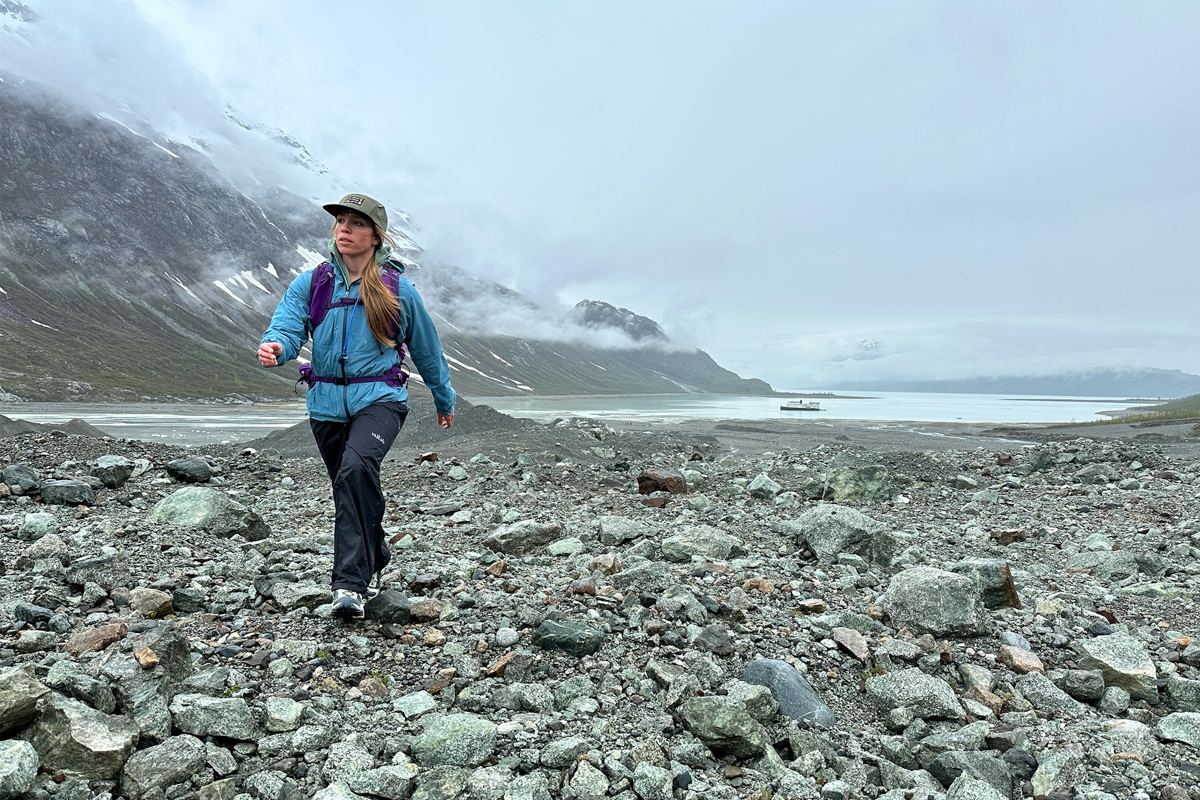 A woman hiking over a rocky landscape in a purple daypack