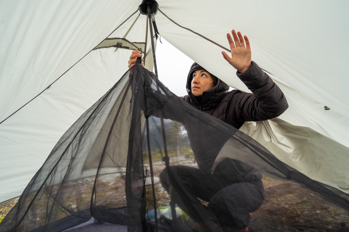 A woman attaching the inner tent to the fly of a backpacking tent