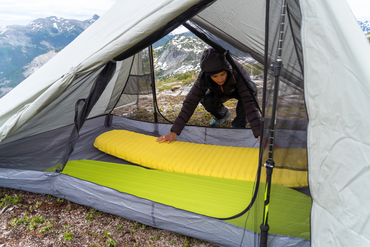 A woman putting sleeping pads in a backpacking tent