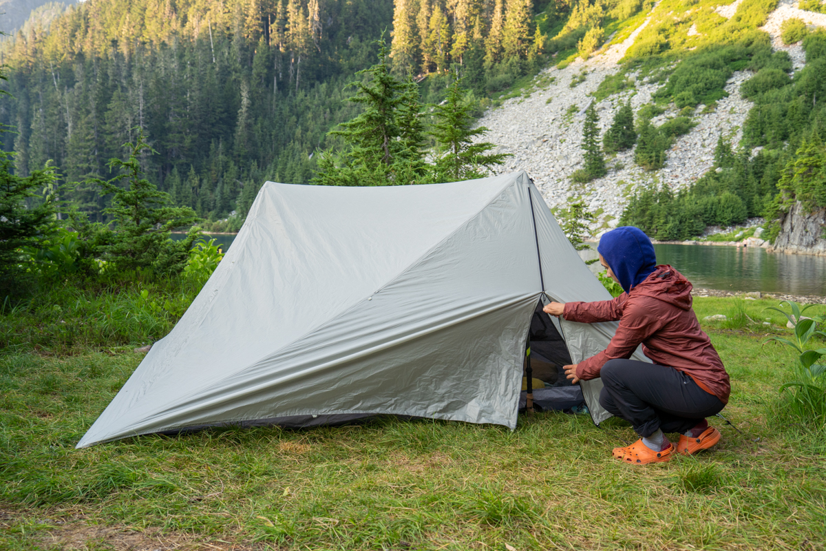 A woman closing the door on a backpacking tent