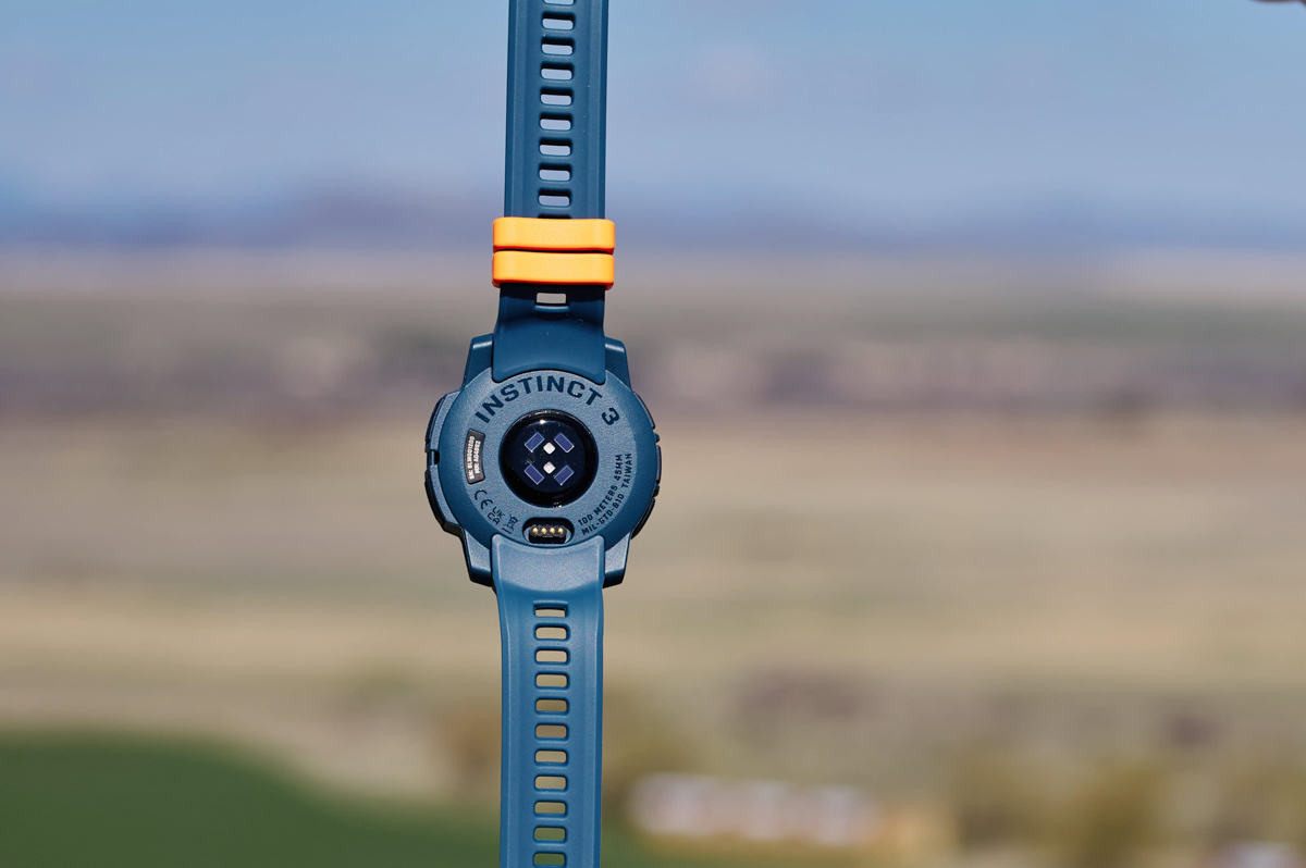 A close up of the heart rate sensor on the back of a blue GPS watch