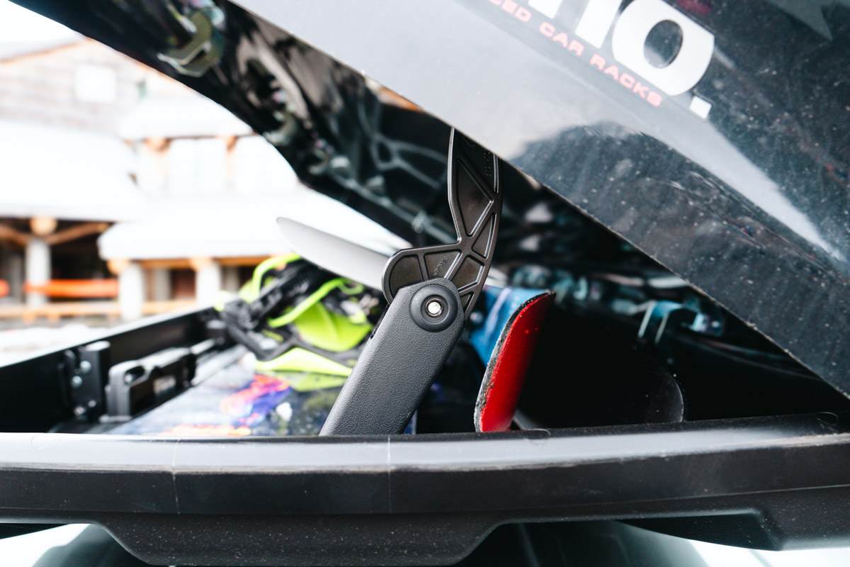 A close-up of the hinge on an open rooftop cargo box