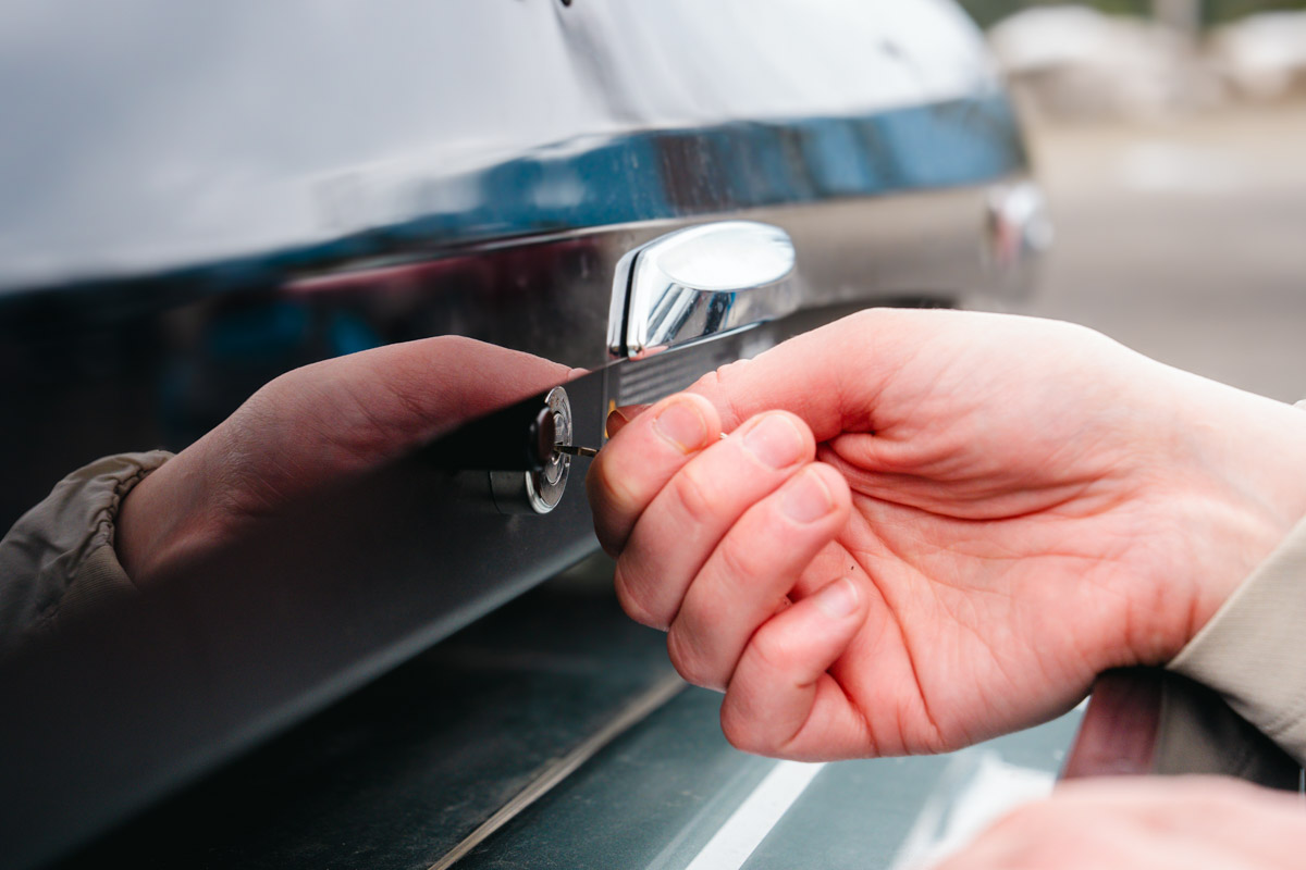A close up of a hand and a key unlocking a cargo roof box