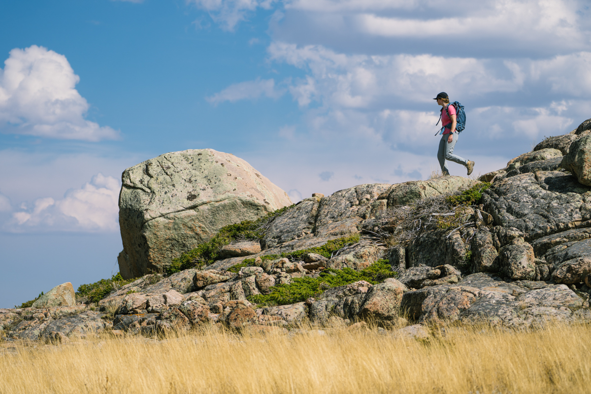A woman hiking down a rocky outcopping in the distance in waterproof hiking boots