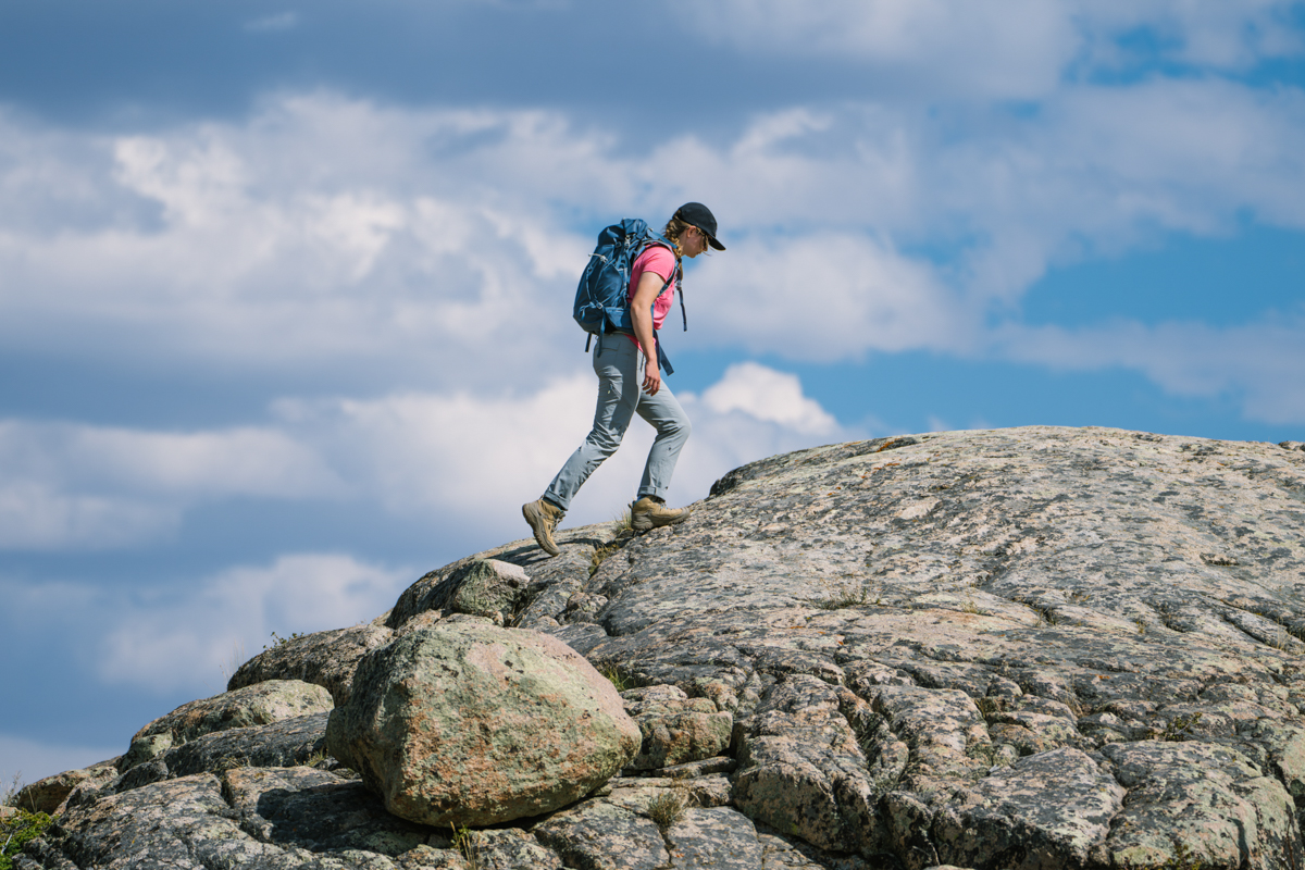 A woman hiking up a rocky outcropping wearing waterproof hiking boots