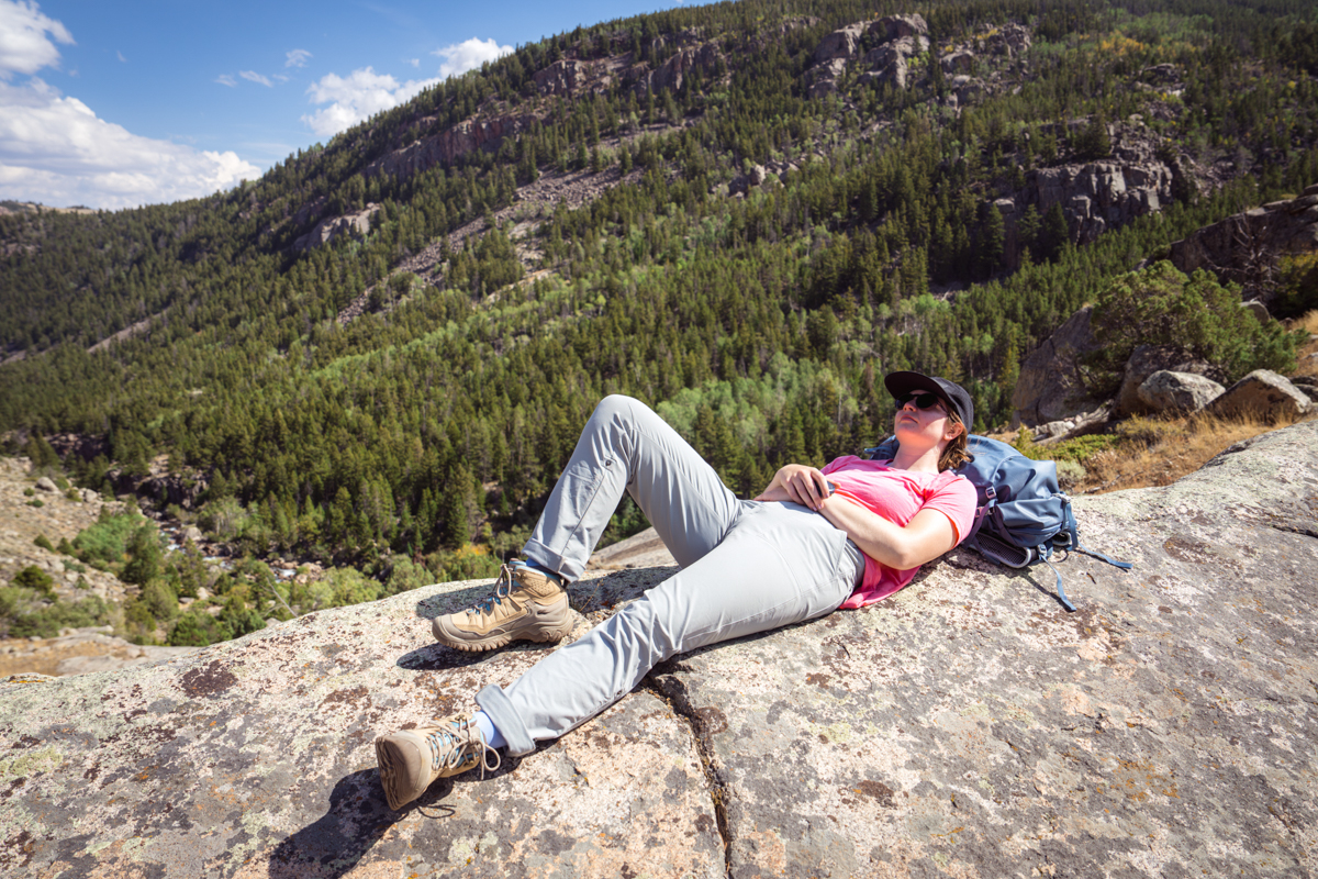 A woman lounging on a rock while wearing a pair of brown waterproof hiking boots