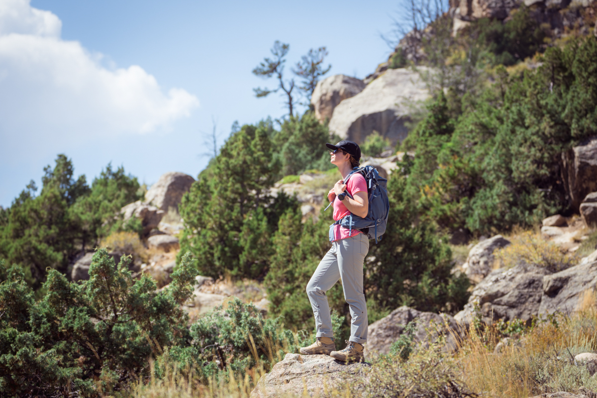 A woman standing on a rocky outcropping wearing waterproof hiking boots