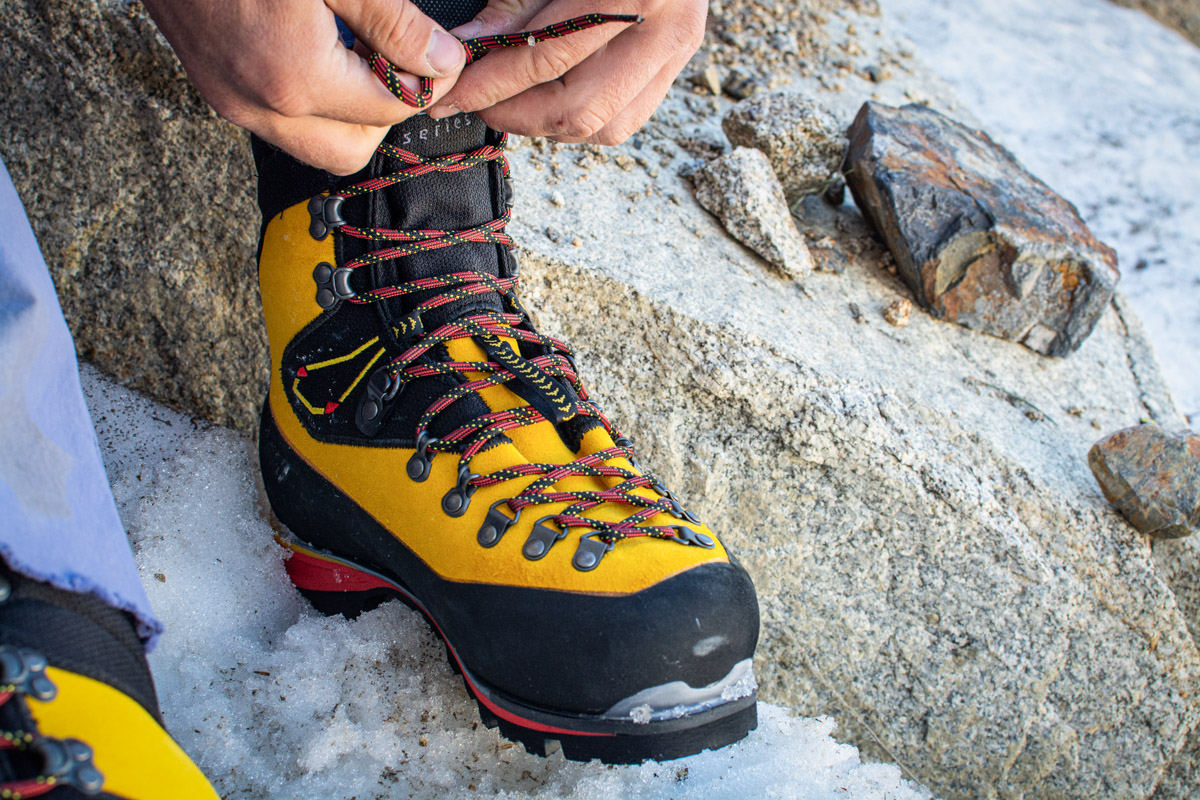 A closeup shot of a man tying the La Sportiva Nepal Cube GTX boots