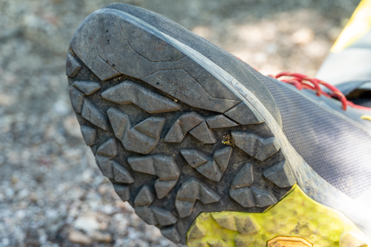 A close up of the outsole on a pair of grey and red approach shoes