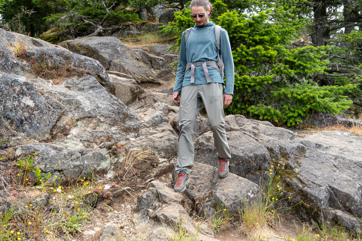 A man hiking down a rocky trail in grey and red approach shoes