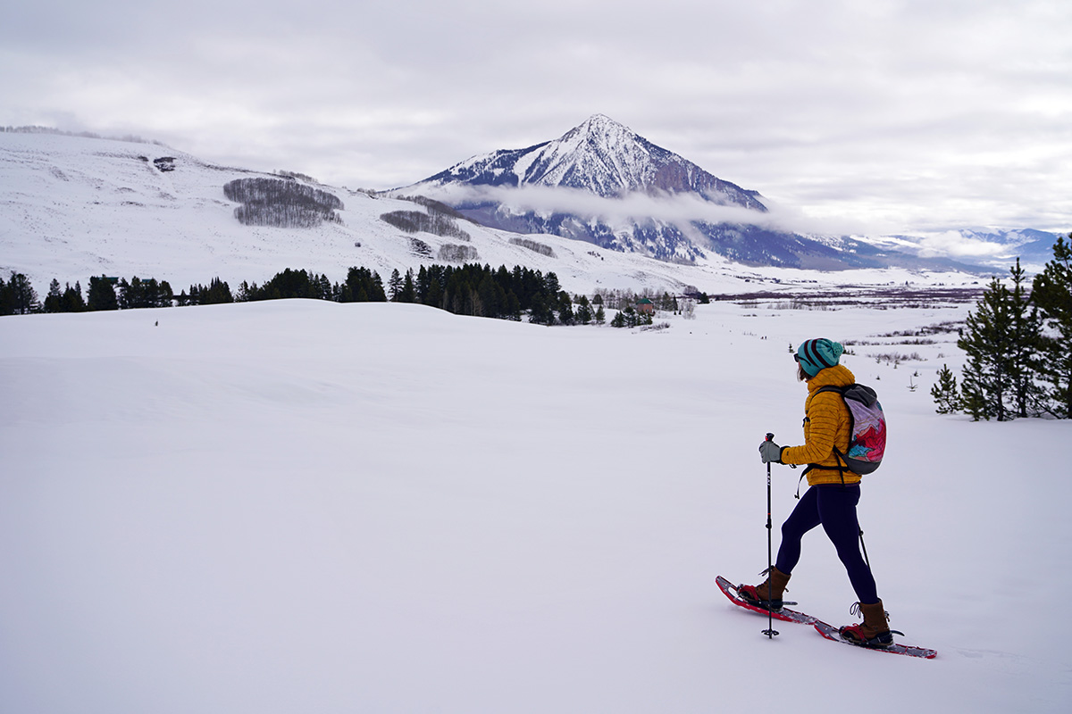 A woman hiking over a snowy meadow in snowshoes