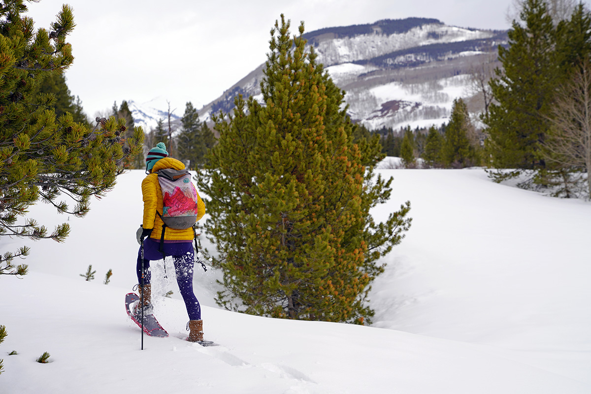 A woman hiking through snowy forest in snowshoes