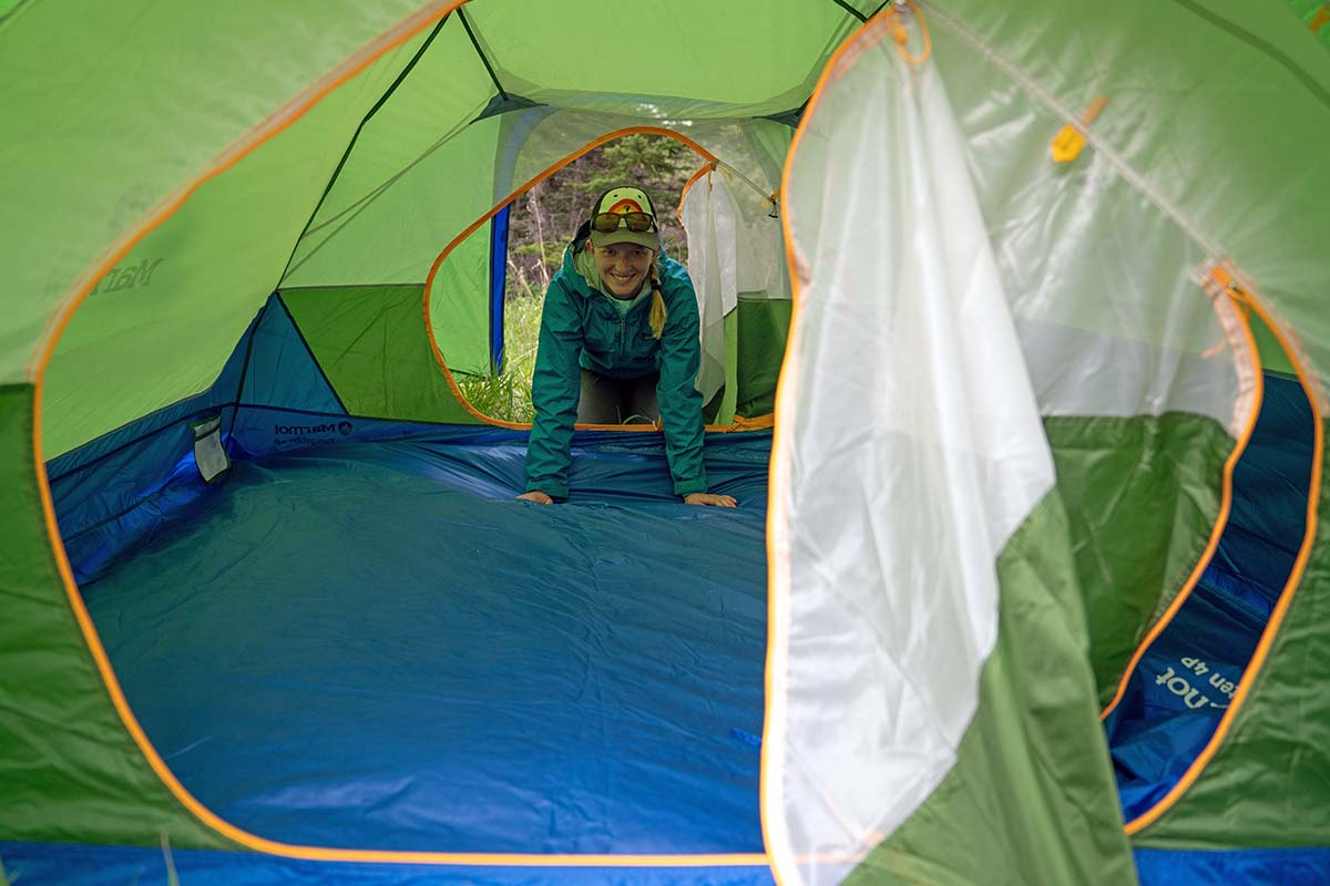 A camper peers happily into her spacious tent setup.