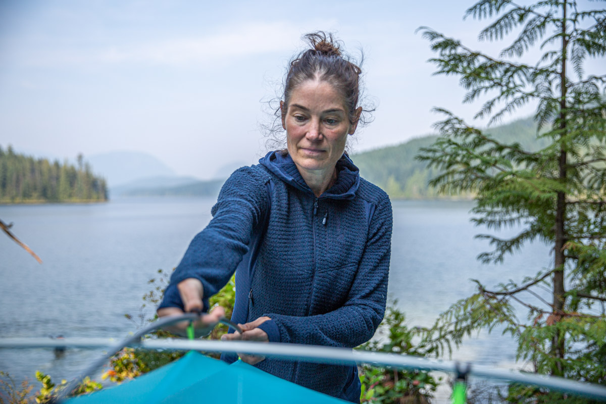 A woman setting up a tent while wearing fleece midlayer