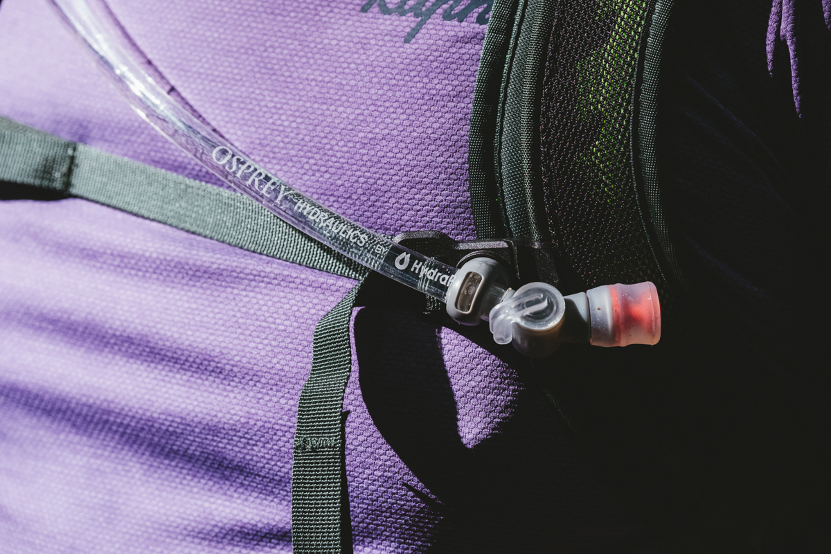 A close up of a hydration hose in a clip on a mountain bike backpack