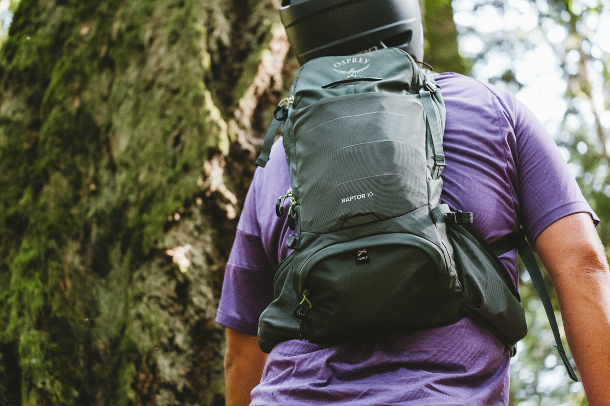A green mountain bike backpack on a man riding a bike through the forest