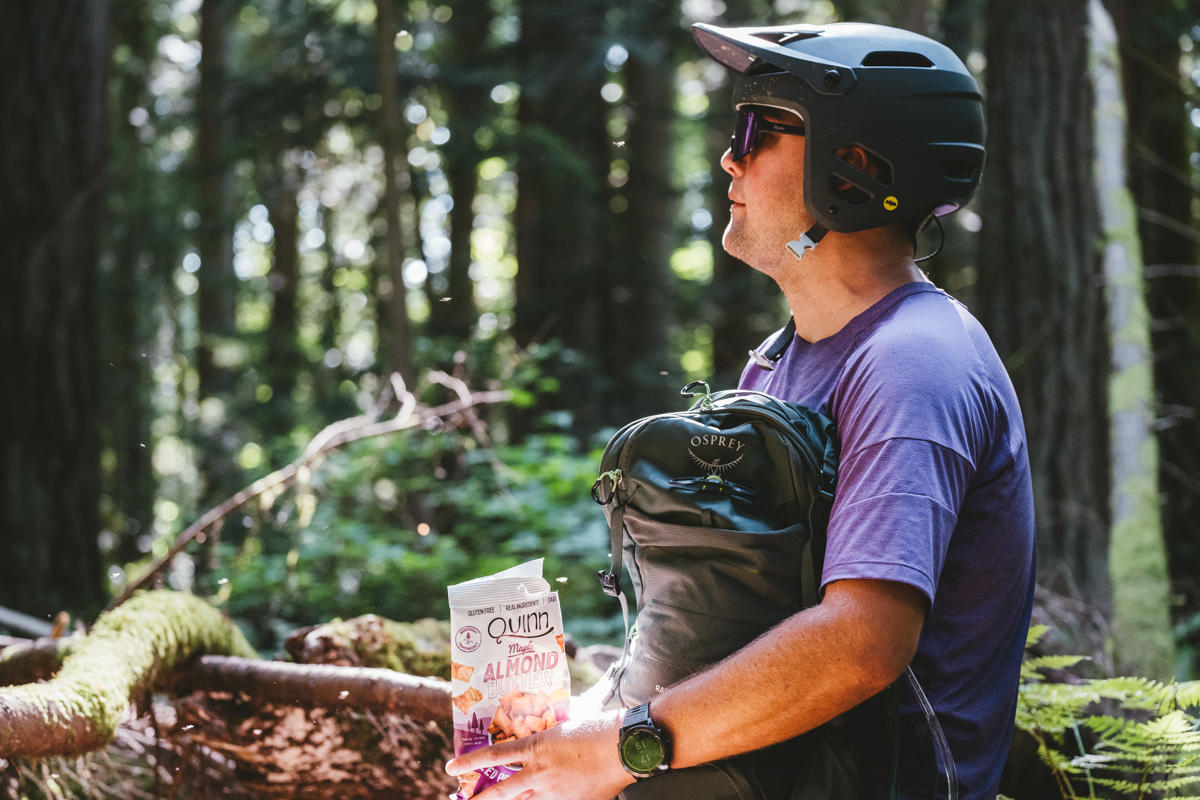 A man holding a bag of nuts and mountain bike backpack in the woods