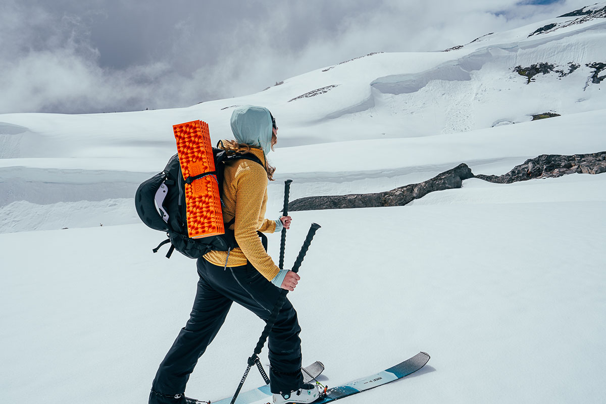 A woman ski touring with full pack in the Patagonia R1 Air Full-Zip Hoody