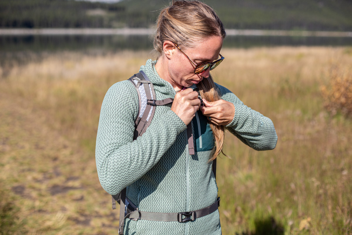 A woman adjusting her backpack while wearing a fleece jacket