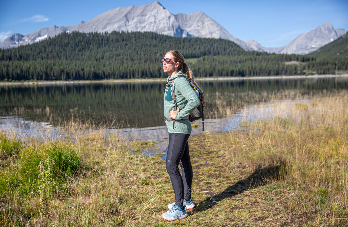 A woman standing in front of a lake wearing a fleece jacket