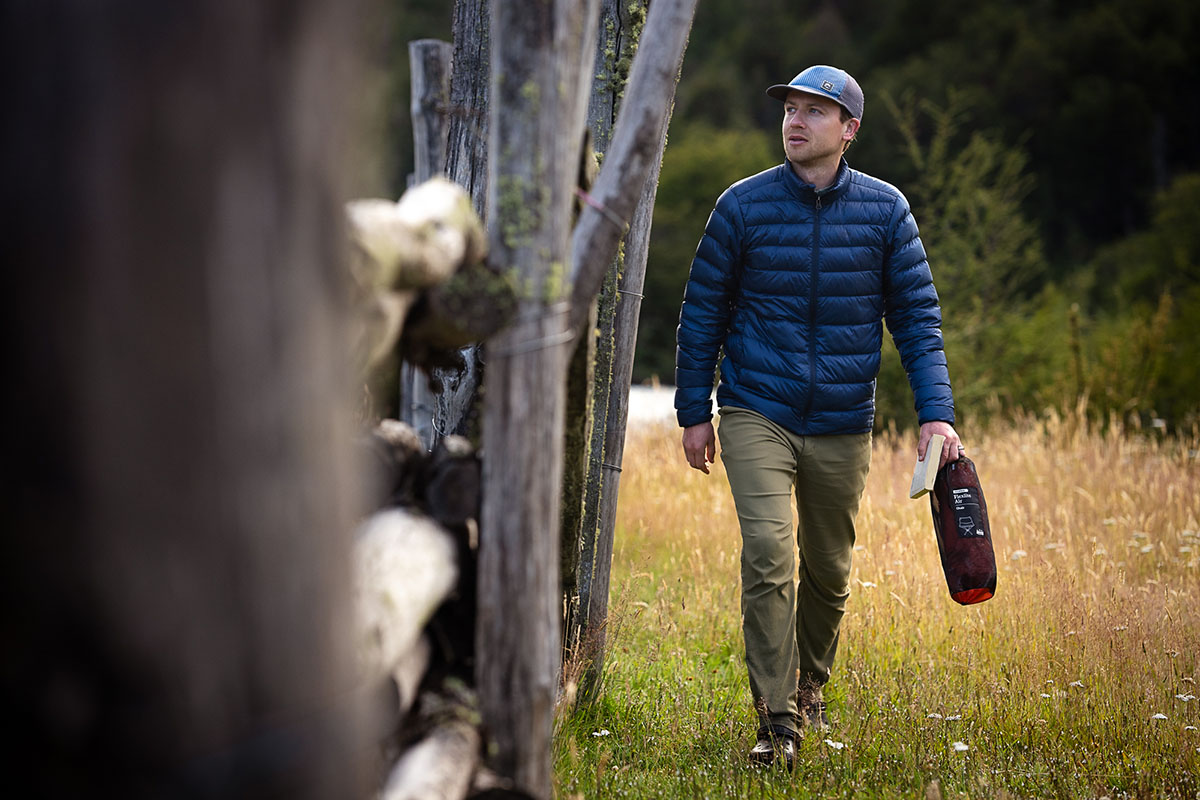 A man walks in a field with the REI Co-op 650 Down Jacket