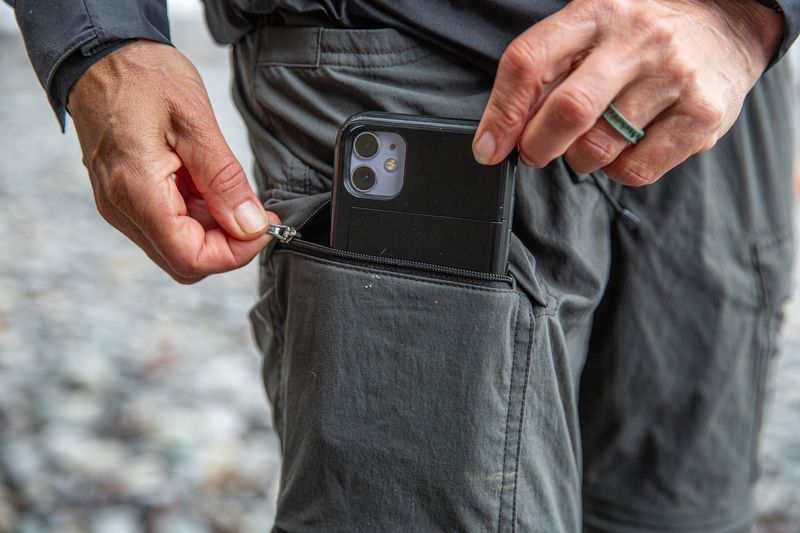 hands put a phone into a pant leg cargo pocket