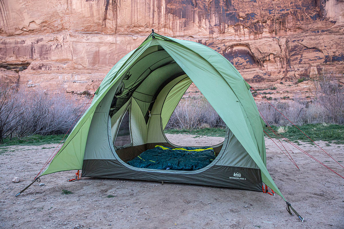 A big, green family tent is pitched next to a red rock canyon.