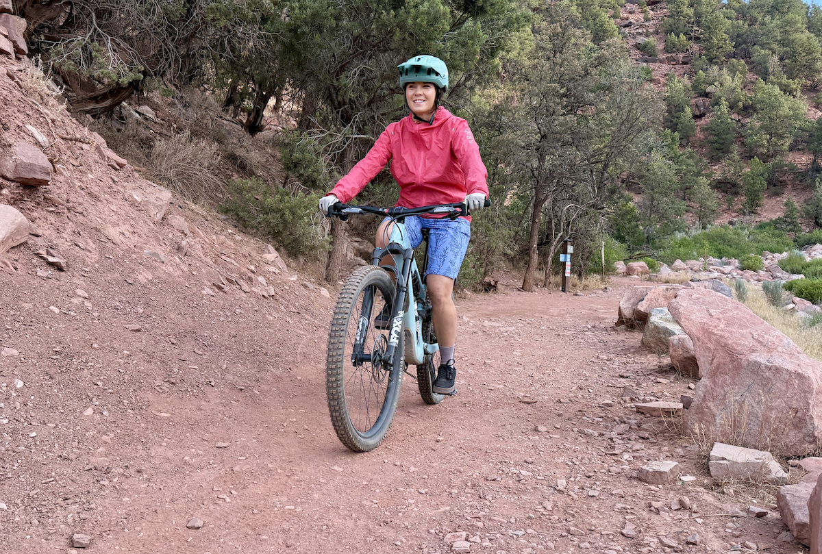 A woman bikes uphill on red dirt