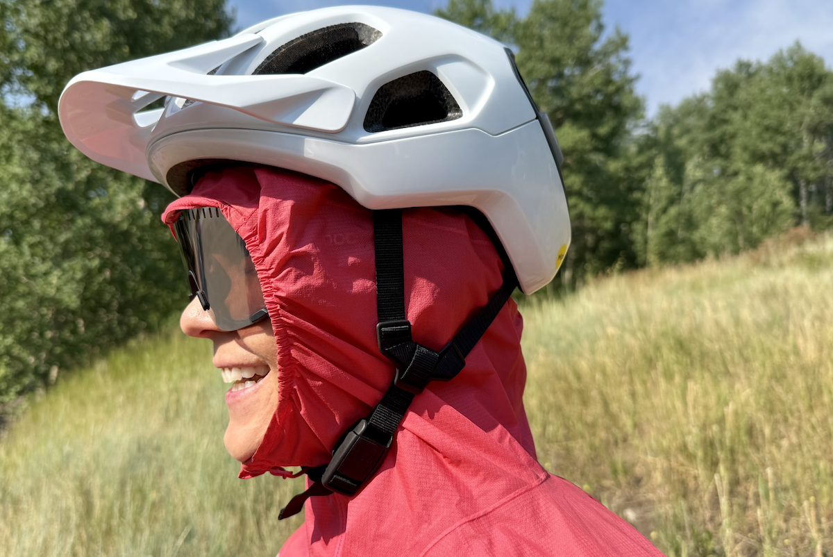 A woman wears a rain jacket hood under her bike helmet