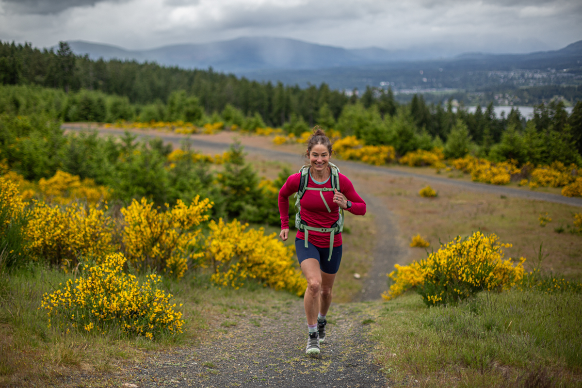A woman running up a step gravel hill in trail running shoes