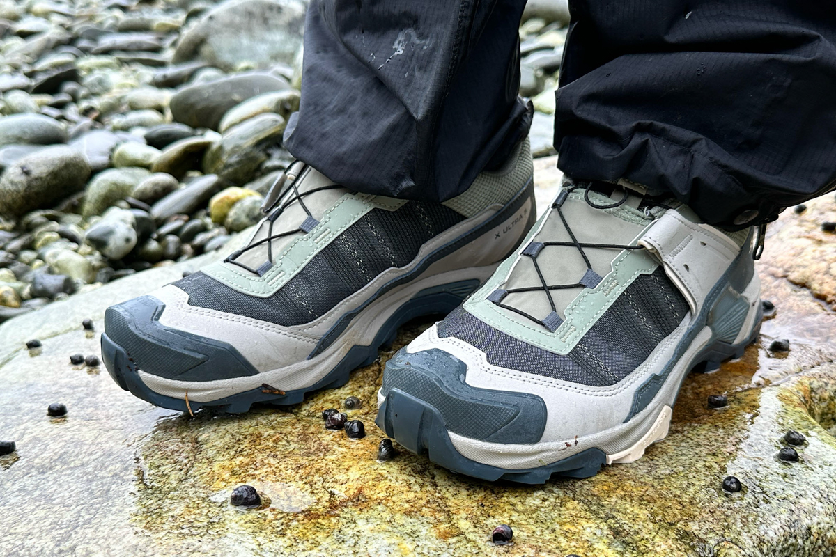 A close up of green and brown Salomon hiking shoes on a rock