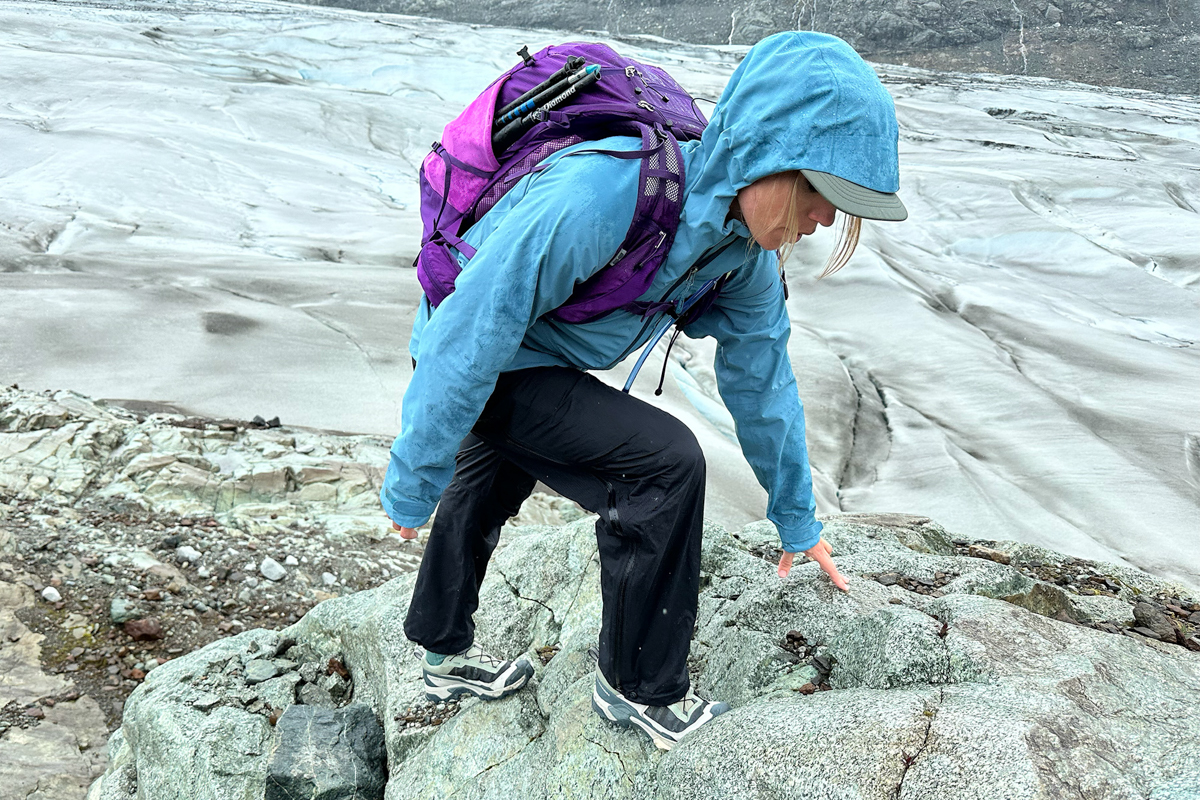 A woman hiking up steep rocky and glacial terrain in hiking shoes