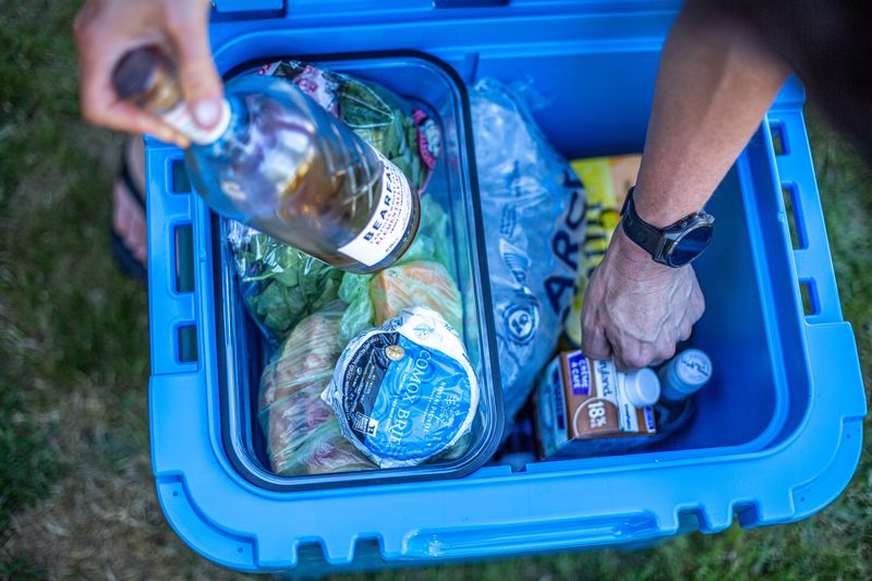A top-down view of a blue cooler full of ice and food