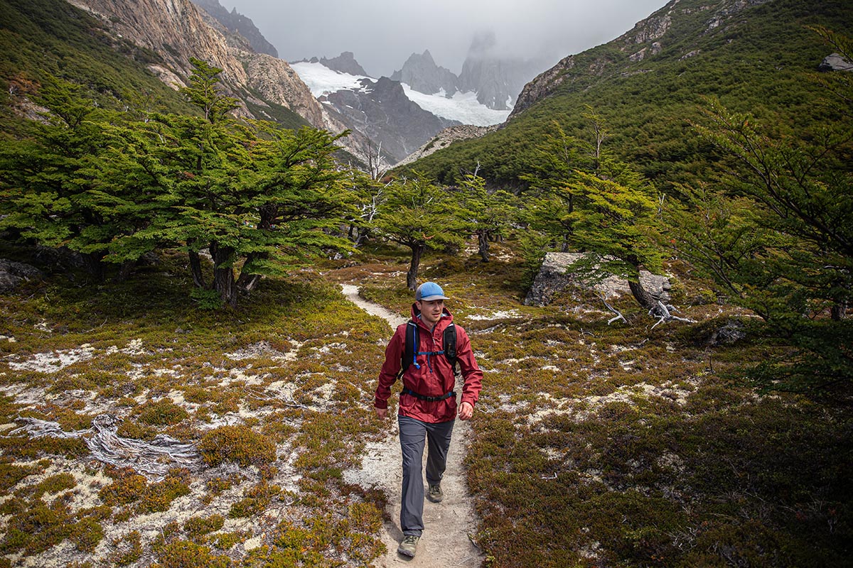 A man hiking through a foggy forest trail in a rain jacket