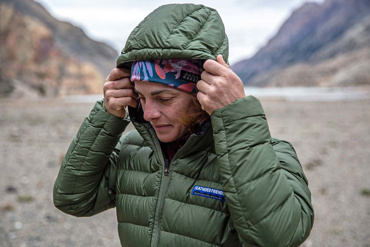 A woman raises the hood on a down jacket to protect against wind.