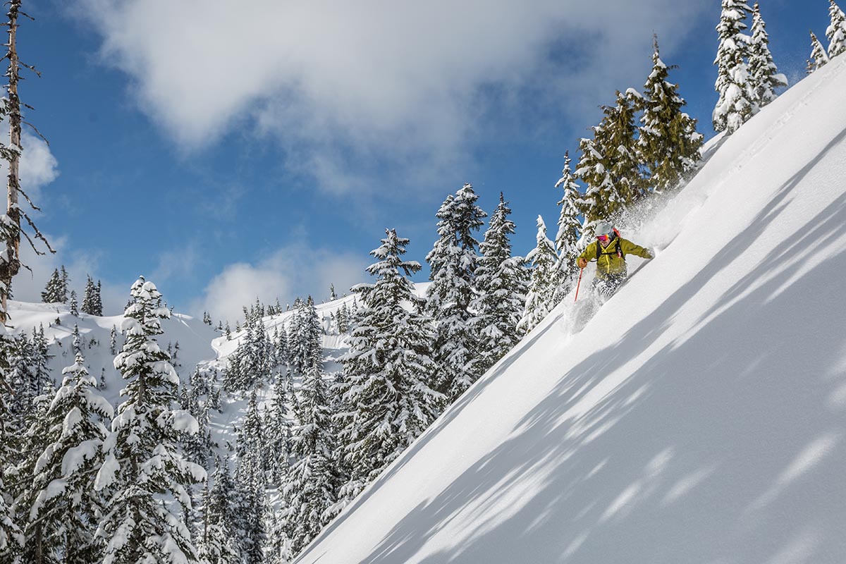 A skier rides down a steep, snow-covered hill.